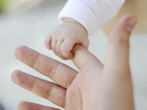 Main de bébé attrapant main adulte